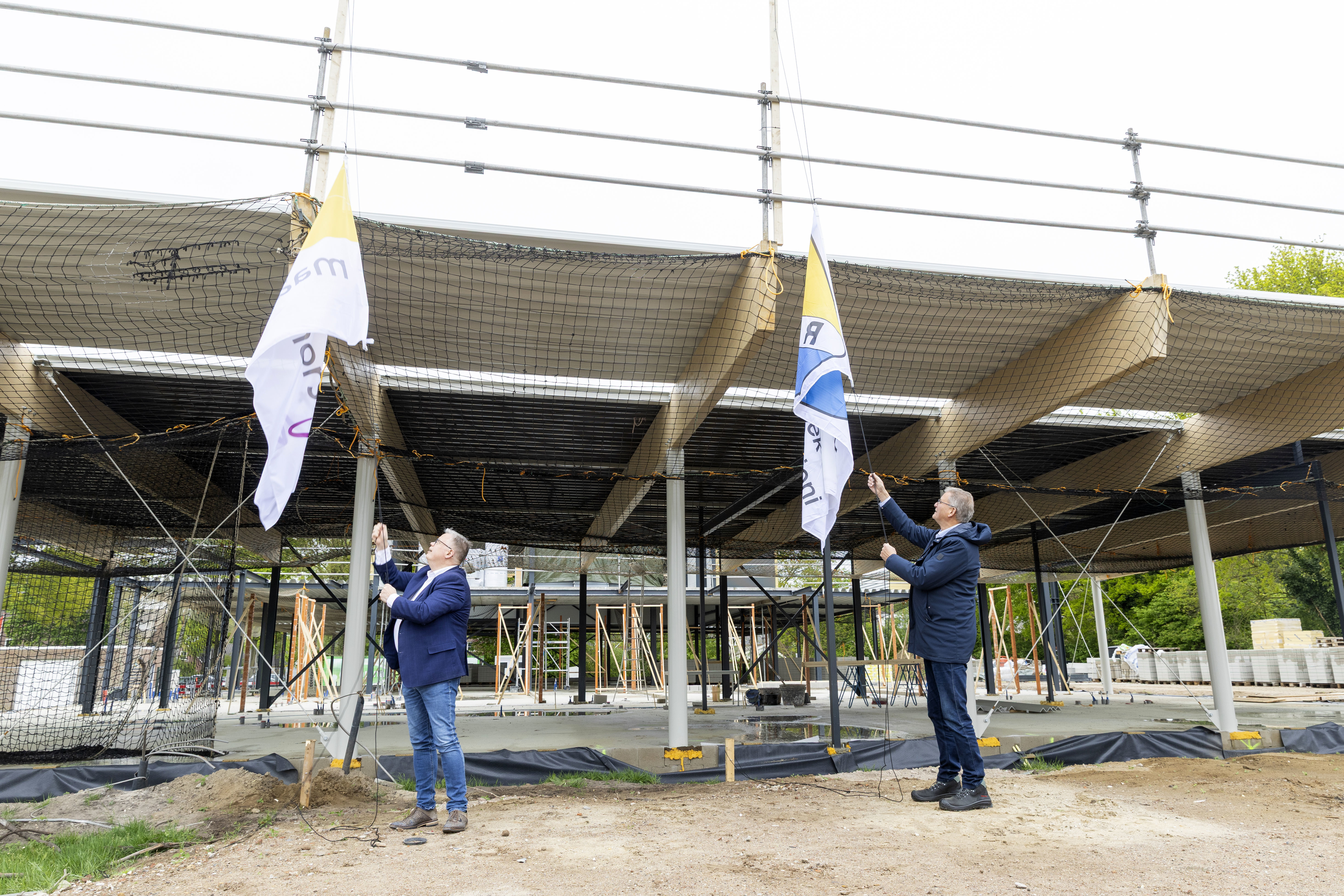 v.l.n.r. wethouder Van den Broek (Sport en Maatschappelijk Vastgoed) en Dominicus van Schaick (voorzitter stichting Sport en Spel Reek) hijsen gelijktijdig de vlag naar het hoogste punt